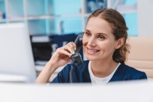 Young female doctor practitioner working at reception desk while answering phone calls